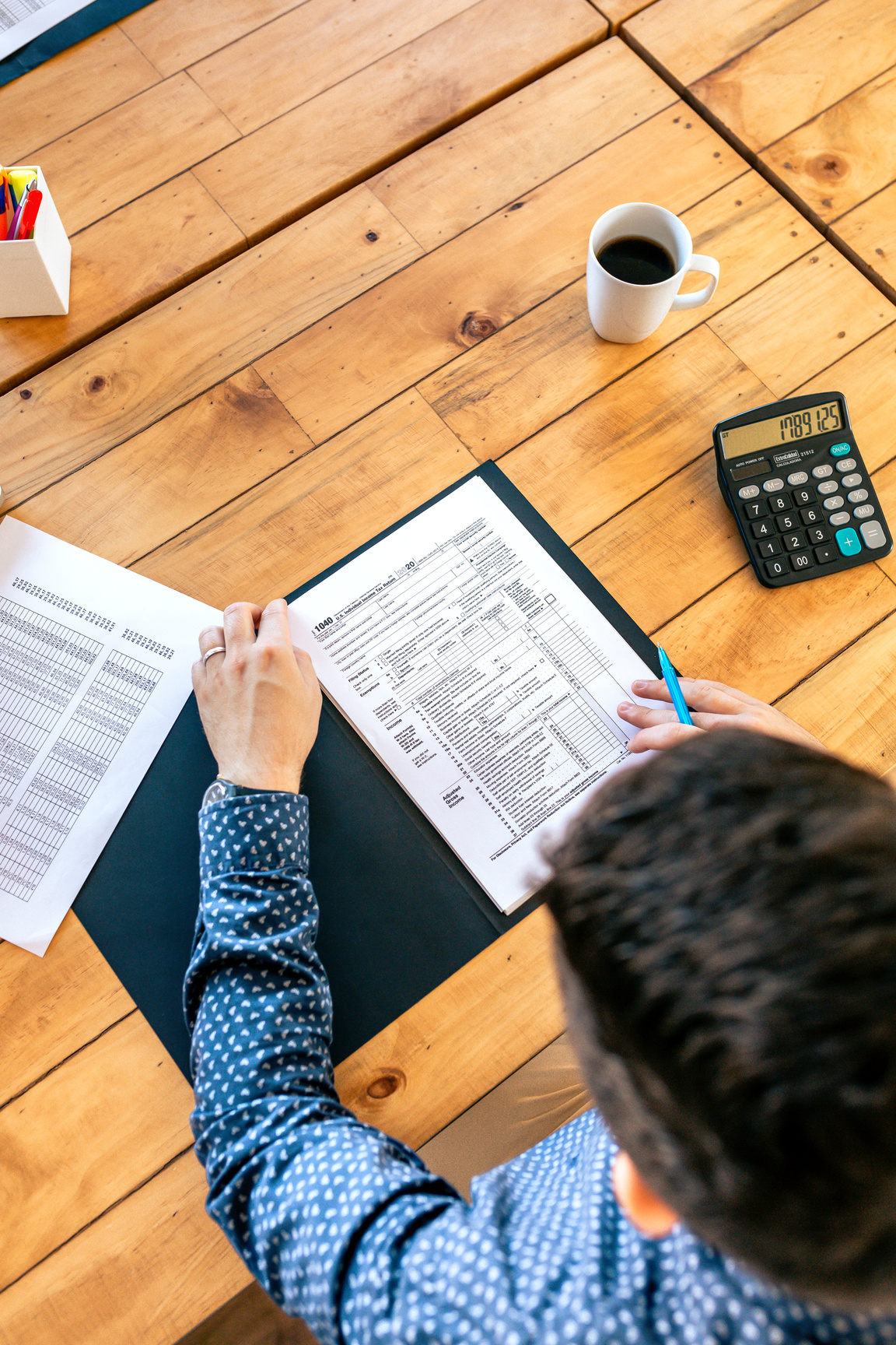 Male Taxpayer Filling in Tax Form on the Table